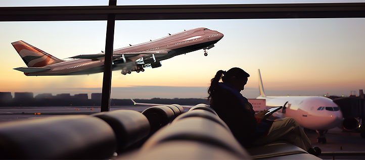 Aus dem Wartebereich eines Flughafens sichtbar hebt ein Flugzeug ab.